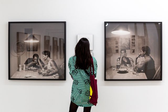 Eine Frau steht vor zwei Bildern der amerikanischen Künstlerin Carrie Mae Weems